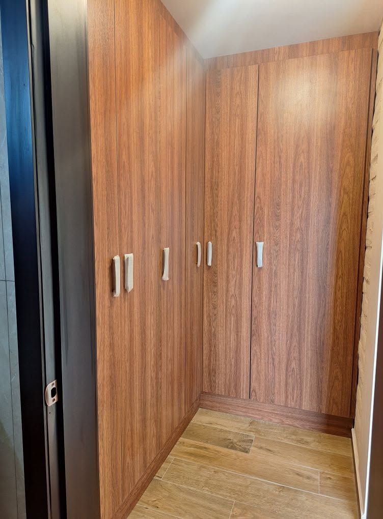 Closet empotrado en L de piso a techo con puertas abatibles en acabado madera