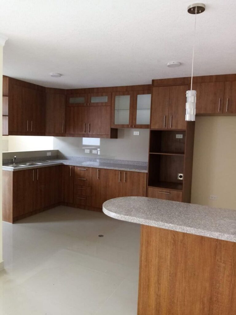Cocina clásica en L de madera cálida con barra desayunador y mesón de granito